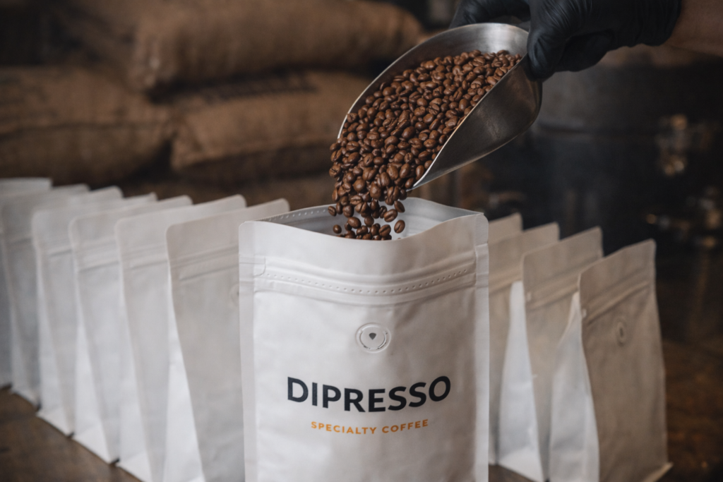 Freshly roasted coffee beans being packaged into DIPRESSO specialty coffee bags